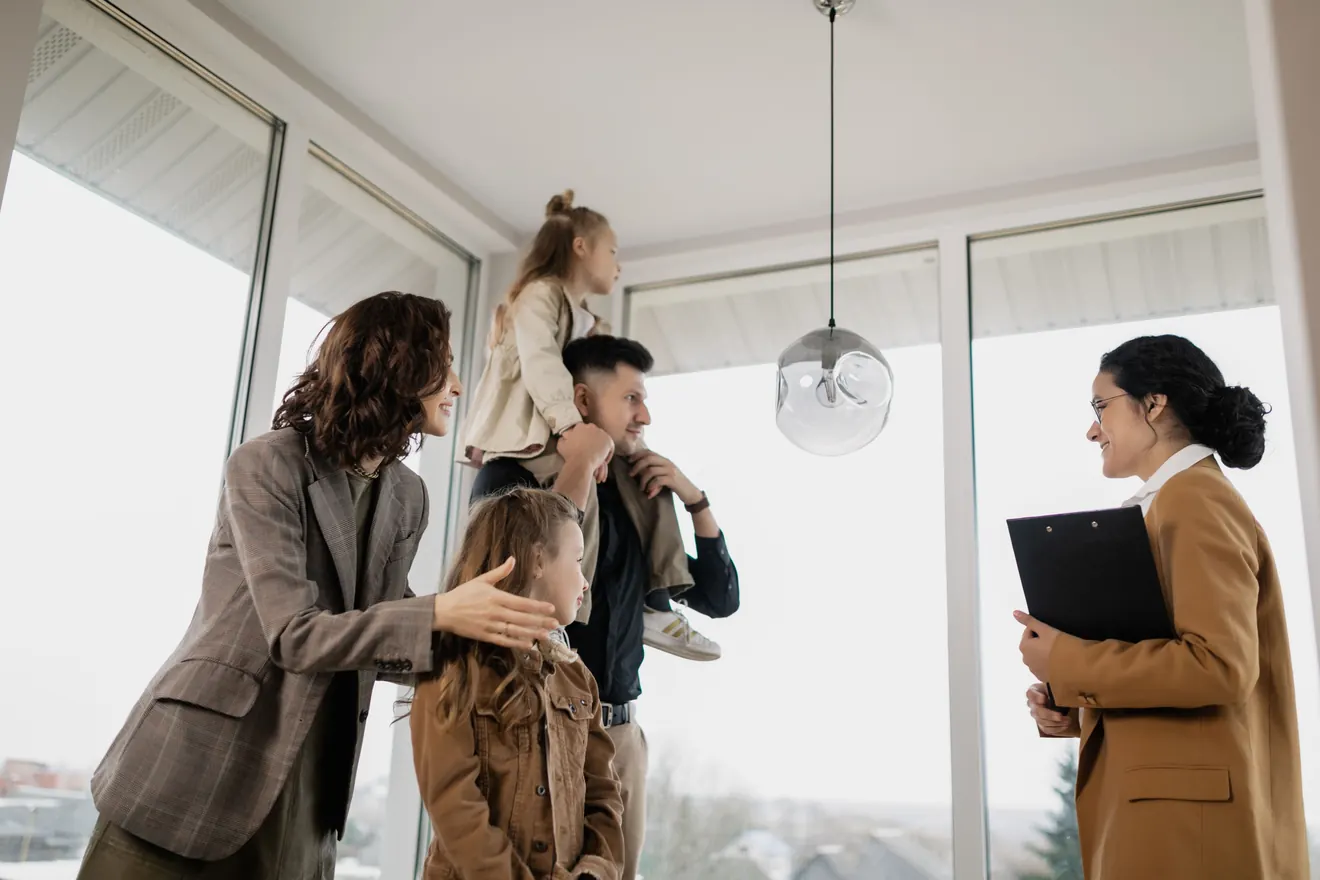 Familie besichtigt gemeinsam mit einer Immobilienberaterin einen hellen Wohnraum